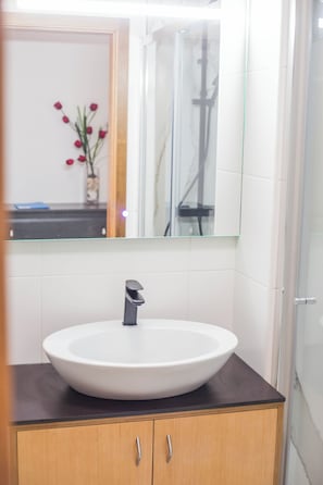 A bathroom with a white sink, a mirror, and a shower.