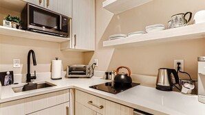 Une cuisine moderne équipée d’un four à micro-ondes, d’un grille-pain, d’une bouilloire, d’une machine à café et d’un lave-vaisselle.