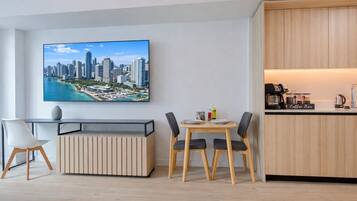 Un salon moderne comprenant un coin repas, un bar à café et un grand tableau représentant un paysage urbain accroché au mur.