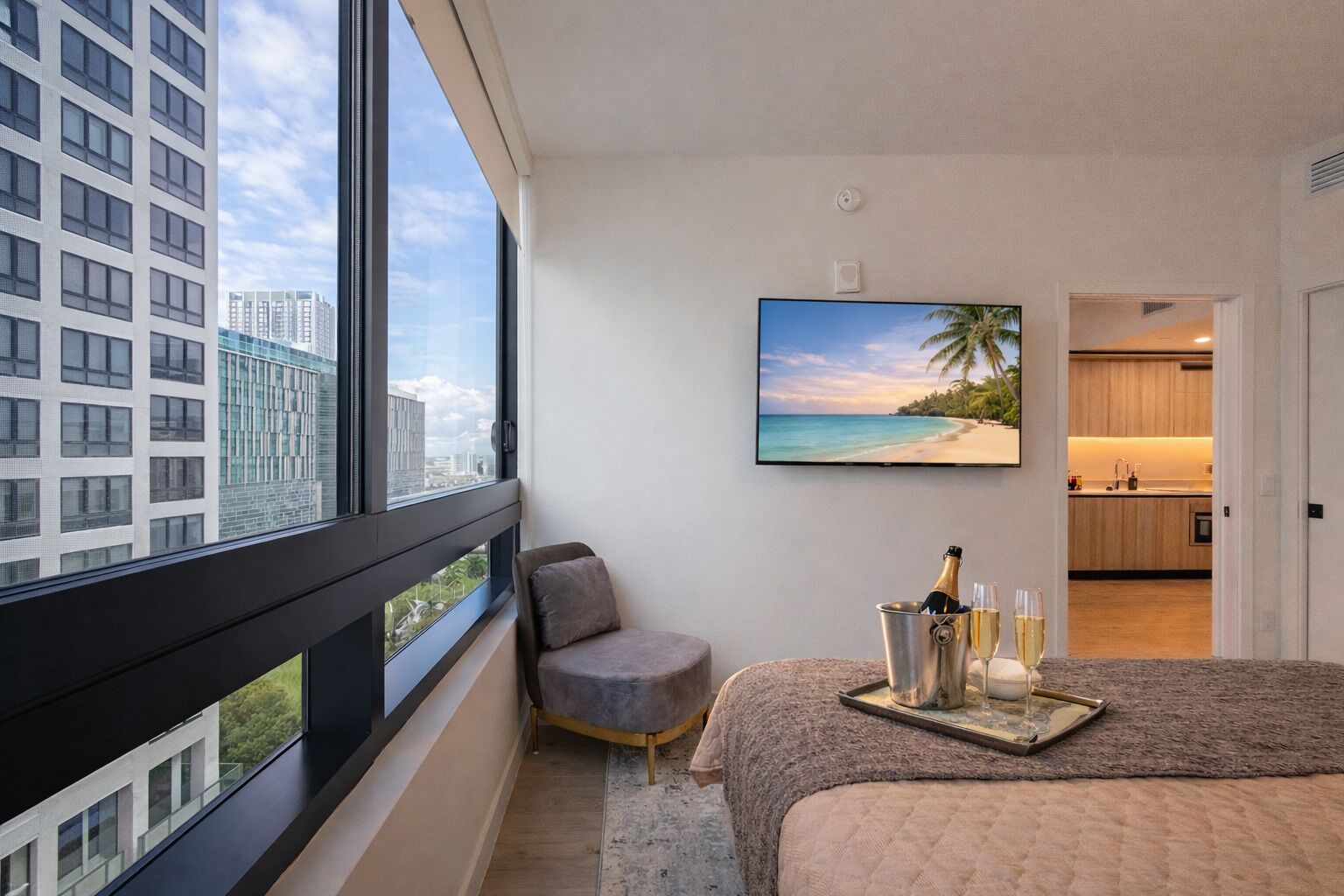 Une chambre d’hôtel moderne dotée d’une grande fenêtre, d’un lit, d’un petit coin salon, d’une télévision et offrant une vue sur la plage.