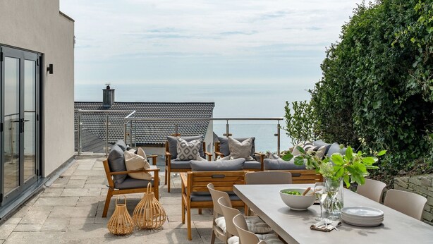 A terrace with outdoor seating, a dining table, and a view of the sea. - Luxury seaside home | 5 mins from beach | sea view | hot tub (Downderry)