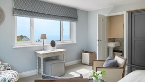 A bedroom with a large window, a bedside table with a lamp, a chair, and a bed. - Luxury seaside home | 5 mins from beach | sea view | hot tub (Downderry)
