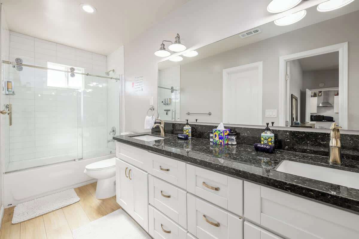 A modern bathroom with a glass-enclosed shower, a white toilet, and a vanity with a black countertop.