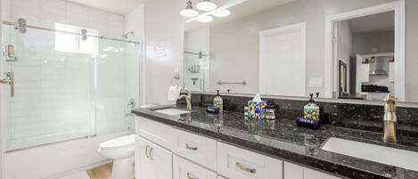 A modern bathroom with a glass-enclosed shower, a white toilet, and a vanity with a black countertop.