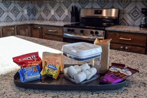 Eine Küchenarbeitsplatte mit verschiedenen Lebensmitteln, darunter Chips, Kakaopulver, Oreos, Marshmallows und Schokoladenriegel.