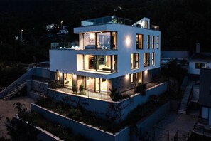 A modern multi-story house with a balcony, large windows, and a staircase leading to the upper levels. - Marvelous panoramic sea view 4-bedroom Villa Opatija Sky on the Opatija Riviera (Bregi)
