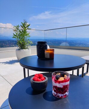 A table with a candle, a bowl of raspberries, and a glass of dessert on a balcony with a city view. - Marvelous panoramic sea view 4-bedroom Villa Opatija Sky on the Opatija Riviera (Bregi)
