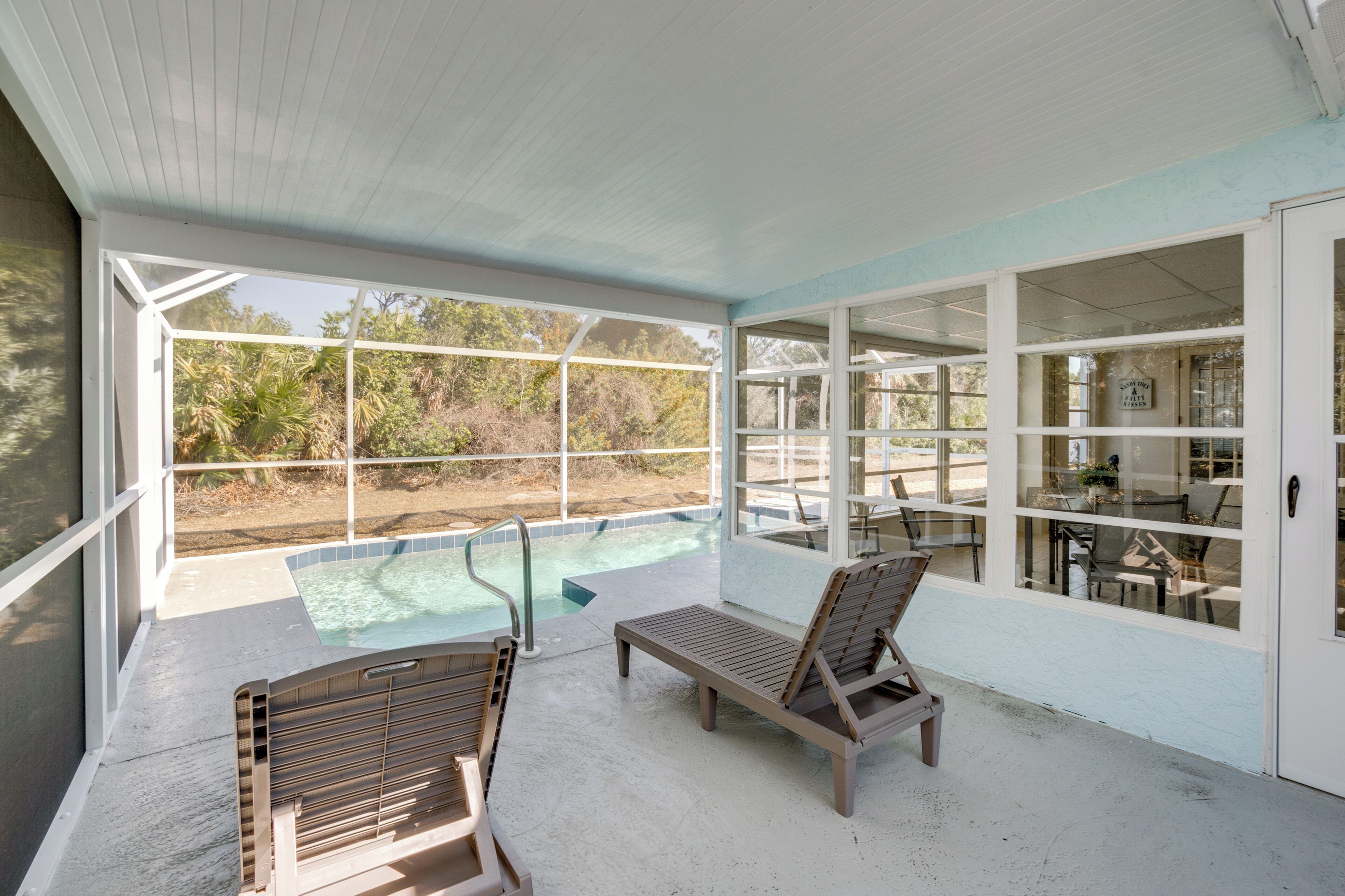 A covered outdoor area with a pool, lounge chairs, and a dining area with tables and chairs.