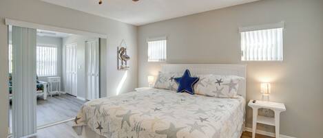 A bedroom with a bed, a ceiling fan, a nightstand, and a window with blinds.