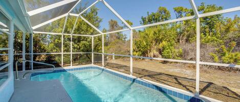 A swimming pool with a covered area, surrounded by trees and vegetation.