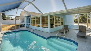 En pool utomhus med tak, som ger fri sikt över omgivningen, inklusive en uteplats med sittplatser och en täckt terrass.
