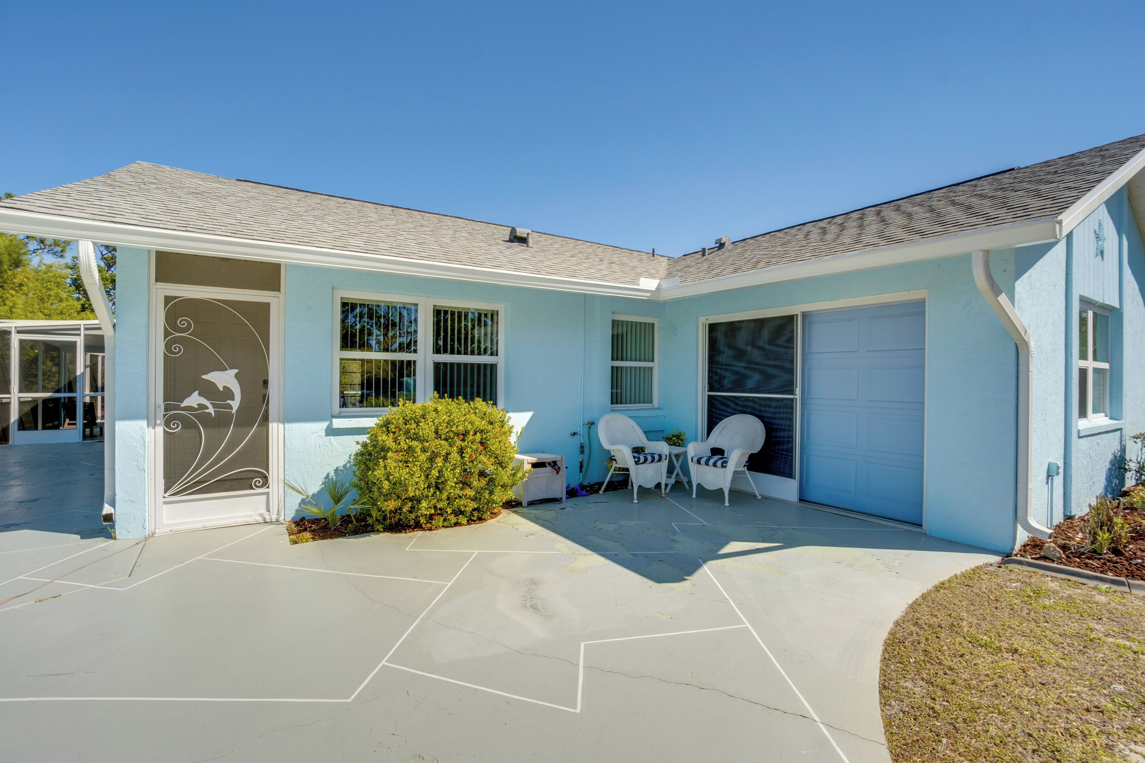 A light blue house with a garage, a covered patio, and a small garden.