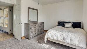 A bedroom with a bed, a dresser, a mirror, and a ceiling fan. - Fully Renovated, Near NMSU! Convenient Family Home (Las Cruces)