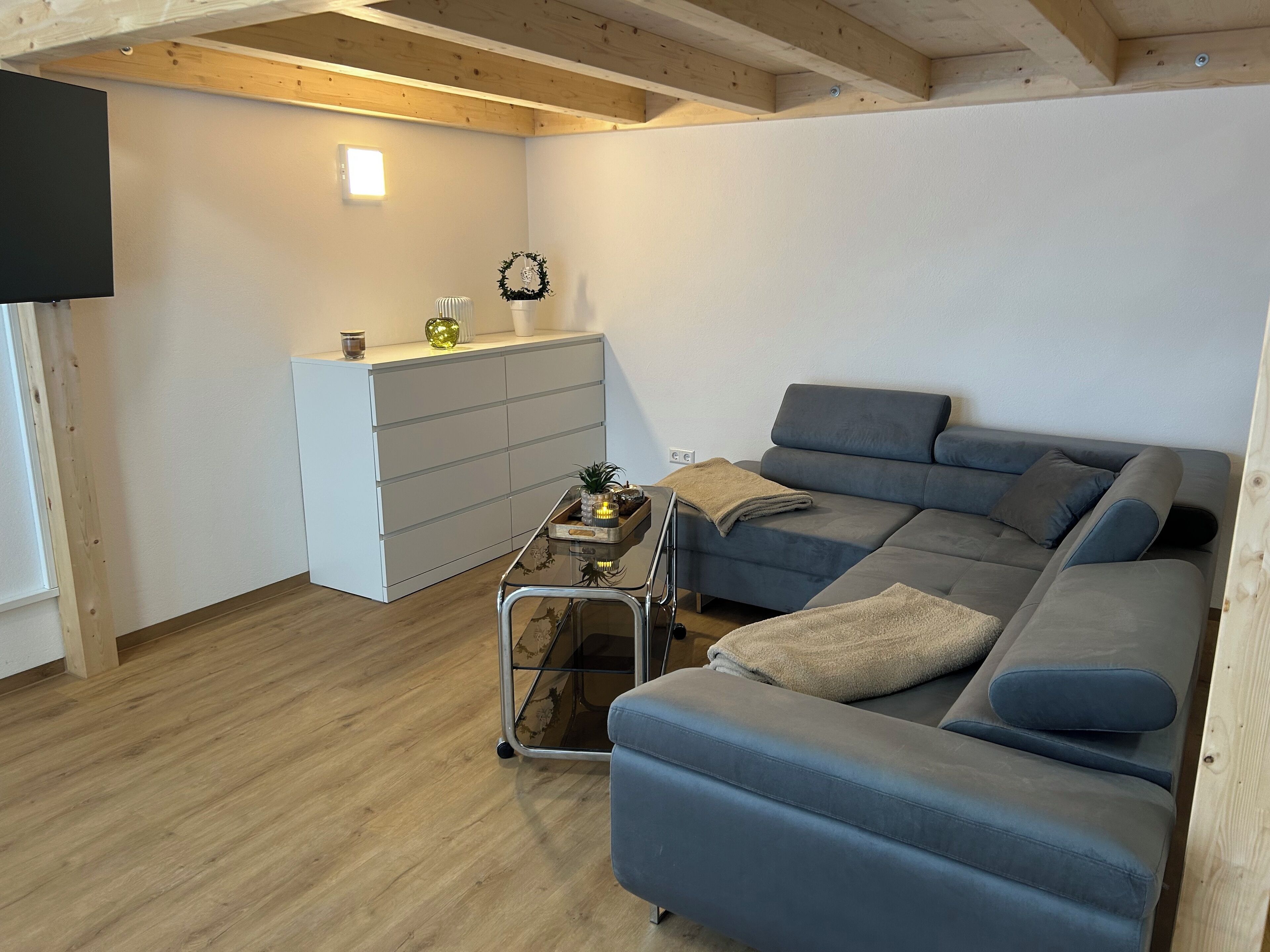 Una sala moderna con un sofá seccional gris, una mesita auxiliar y un mueble blanco.