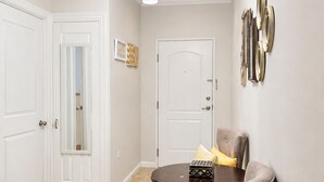 A hallway with a round table, a chair, and a door. - Exquisite One-bedroom Condo • City View • Port of Spain • Modern • Vibrant • (Port of Spain)