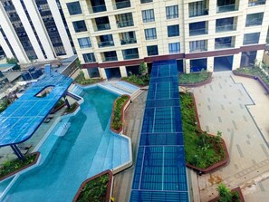 A rooftop pool area with a blue water slide, surrounded by greenery and solar panels. - Kilimani - The Elegant Eyrie near Yaya Center (Nairobi County)