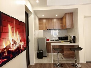 A compact kitchen with wooden cabinets, a refrigerator, a microwave, and a coffee maker. - Kilimani - The Elegant Eyrie near Yaya Center (Nairobi County)