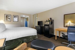 A hotel room with a bed, a desk, a chair, a television, a dresser, and a mirror. - Stay Express Inn & Suites Tyler (Tyler)