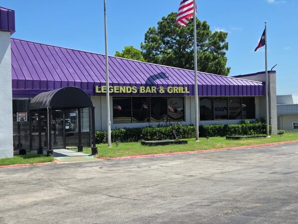 Um restaurante chamado Legends Bar & Grill, com toldo roxo e entrada coberta.