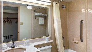 A bathroom with a sink, mirror, toilet, shower, and a towel rack.