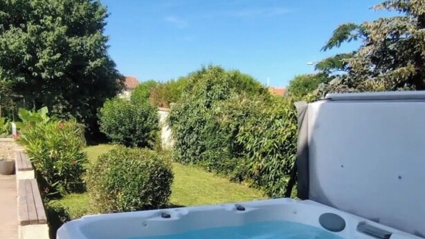Una vasca idromassaggio in un giardino sotto un cielo azzurro limpido.