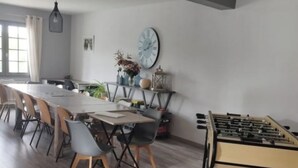 Zona pranzo moderna con un tavolo lungo e sedie, un tavolo da calcio e un orologio appeso al muro.