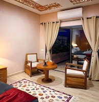 A cozy room with a wooden chair, a small round table, and a bed.