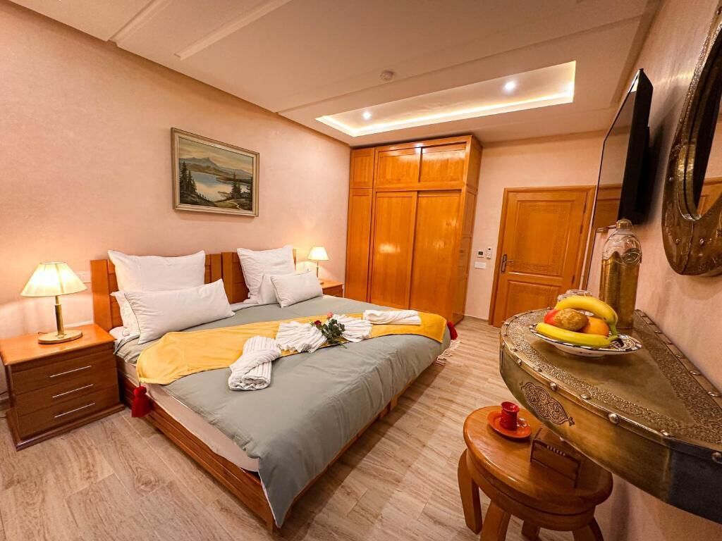 A hotel room with a bed, bedside tables, a desk, and a mirror.