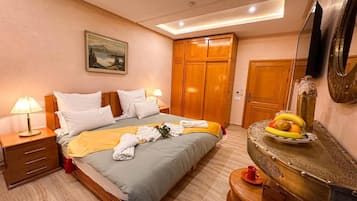 A hotel room with a bed, bedside tables, a desk, and a mirror.