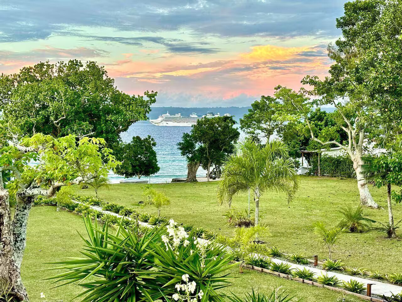 Un jardin luxuriant offrant une vue sur un navire de croisière sur l’eau.