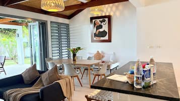 A modern kitchen with a dining area, a sofa, and a coffee table with milk and water bottles.