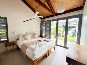 A bedroom with a bed, a ceiling fan, a window, and a view of the outdoors.