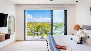 A modern bedroom with a large bed, a TV, and a balcony with a table and chairs.