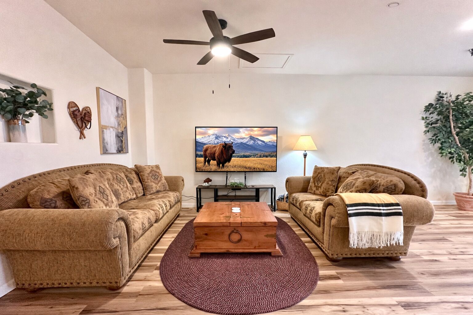 A living room with two sofas, a coffee table, a TV, and a ceiling fan.