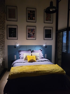 Une chambre à coucher avec un lit, une tête de lit et des lampes fixées au mur.