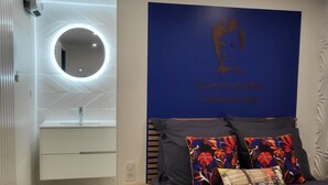 Quarto moderno com cama, mesa de cabeceira, espelho e uma obra de arte na parede.