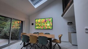 Uma área de refeições com mesa e cadeiras, uma janela grande e uma obra de arte colorida na parede.