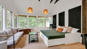 A modern bedroom with a large bed, a sofa, and a dining table.