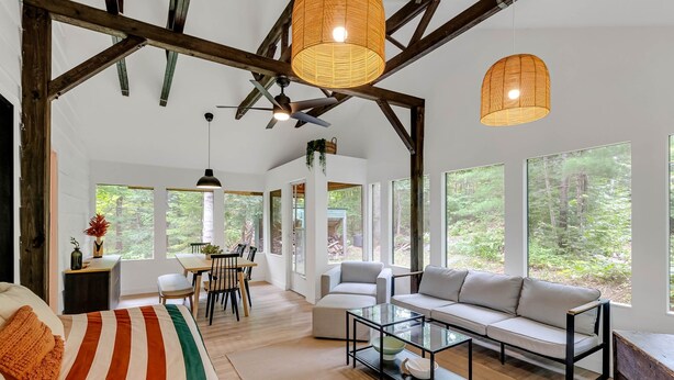 A spacious living room with a large sofa, a glass coffee table, and a dining area with a table and chairs.