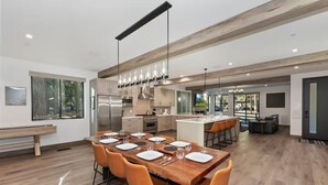 Una cucina moderna con isola centrale, tavolo da pranzo in legno con sedie arancioni e un'ampia finestra che si affaccia su un giardino.