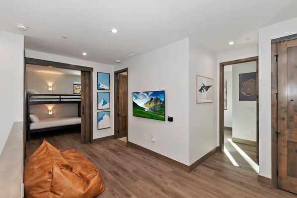 Een moderne kamer met een stapelbed, een zak stoel en kunstwerken in lijsten aan de muren.