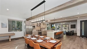 Une cuisine moderne avec un îlot central, une table à manger en bois et des chaises orange.