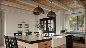 Een moderne keuken met een centraal eiland, houten kastjes en hanglampen.