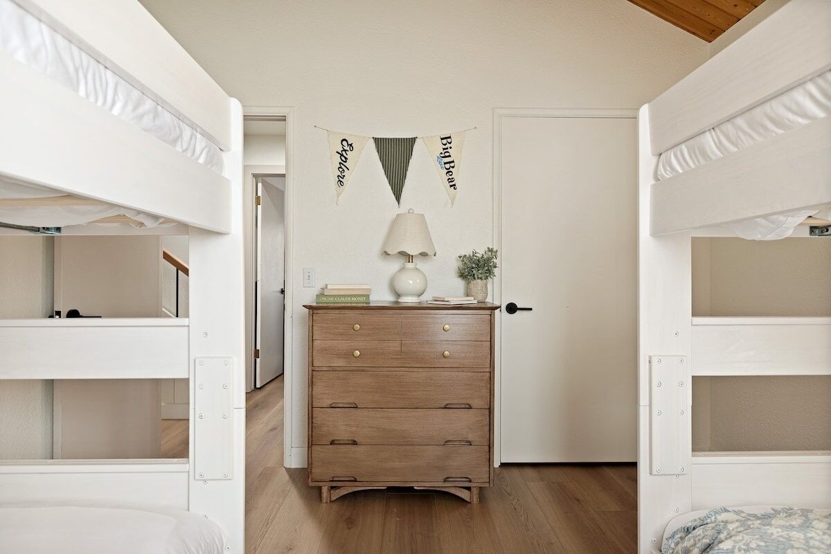 Habitación con literas, un aparador de madera, una lámpara y una puerta decorada con un cartel.