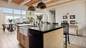 Een ruime keuken met een groot eiland, houten balken in het plafond en hanglampen.