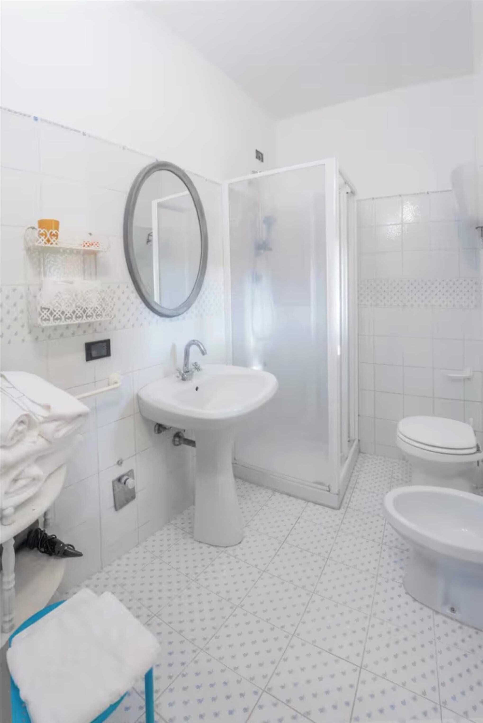 Un baño con lavamanos, espejo, inodoro y ducha.
