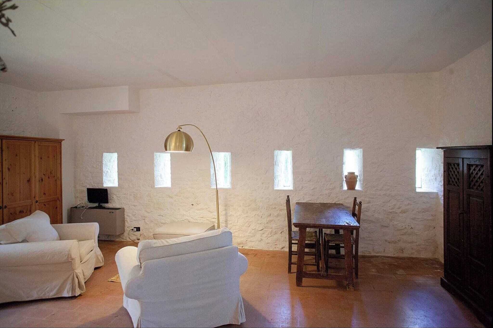 A room with white walls, a wooden cabinet, a table with chairs, and a floor lamp.