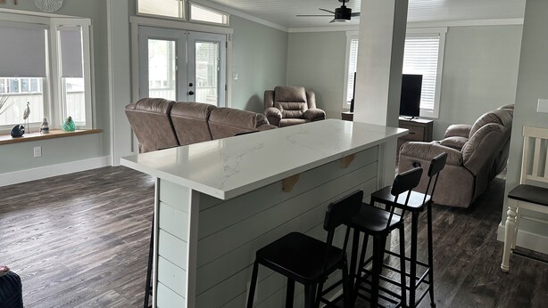 A spacious kitchen with a central island, bar stools, a sofa, and a recliner. - Delightful 5-bedroom house within Oceanside Village in Surfside Beach (Surfside Beach)