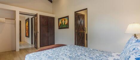 A bedroom with a bed, wooden wardrobe, and a door.