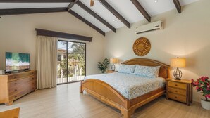 A bedroom with a wooden bed, a ceiling fan, an air conditioning unit, a TV, and a view of the outside. - Casa Luz de Luna (Tempate)